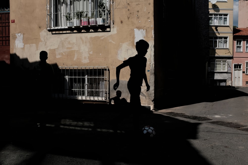 Silueta de niño corriendo cerca de un edificio de hormigón marrón durante el día