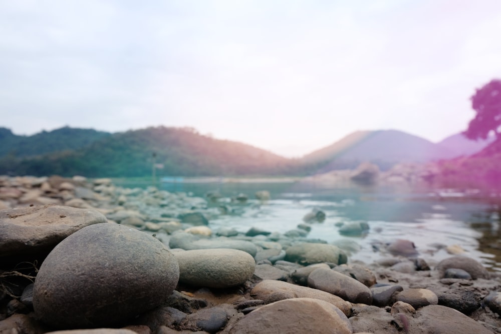 photo of body of water surrounded with rocks and mountain range