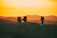 A group of hikers reaching the summit of Mount Rinjani at sunrise, with vibrant orange skies.