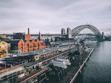 aerial photography of concrete buildings and bridge beside ocean under cloudy sky
