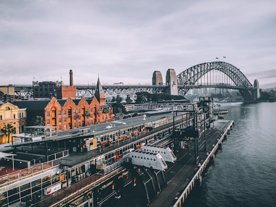 aerial photography of concrete buildings and bridge beside ocean under cloudy sky
