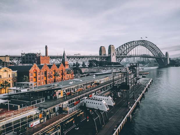 aerial photography of concrete buildings and bridge beside ocean under cloudy sky