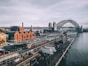 aerial photography of concrete buildings and bridge beside ocean under cloudy sky
