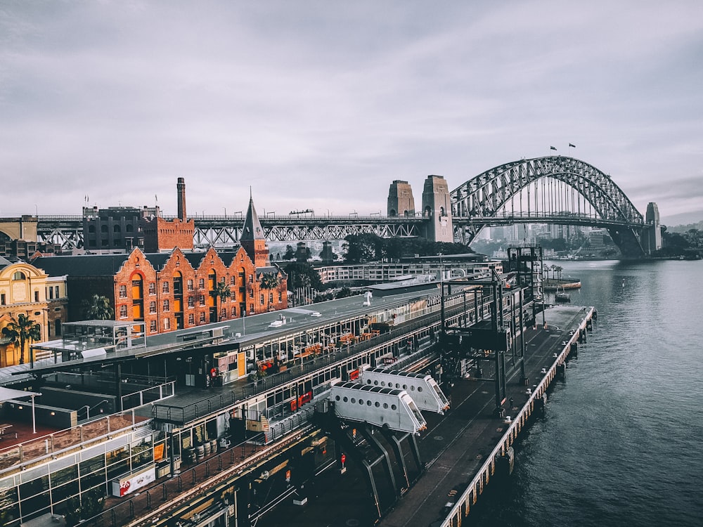 aerial photography of concrete buildings and bridge beside ocean under cloudy sky