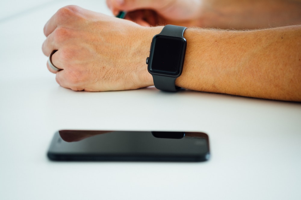 black smartphone near person's hand wearing black smartwatch