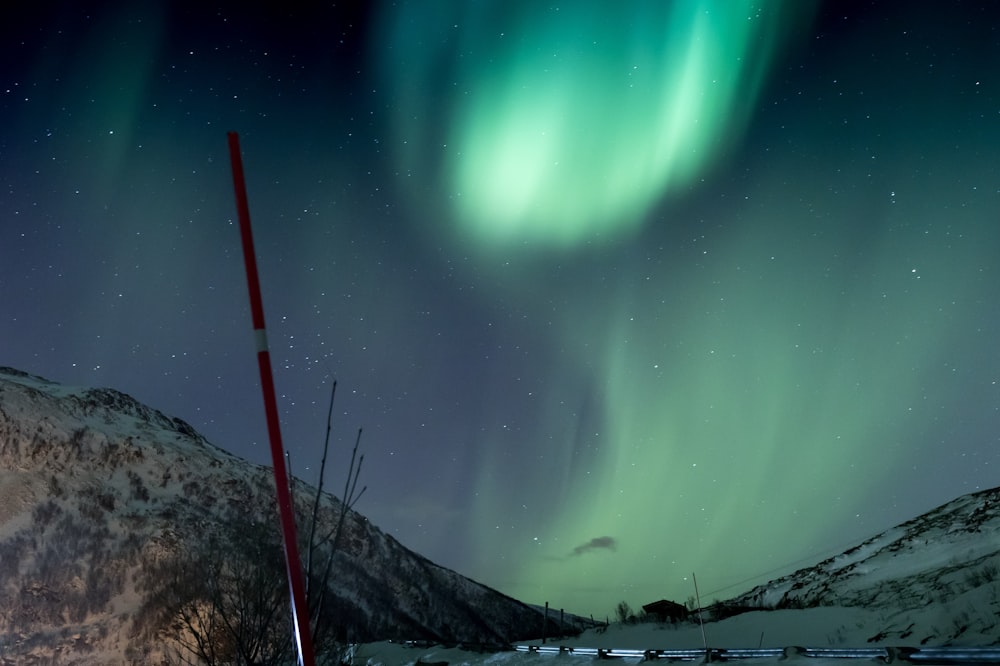 Aurora Borealis about mountain range covered with snow during nighttime