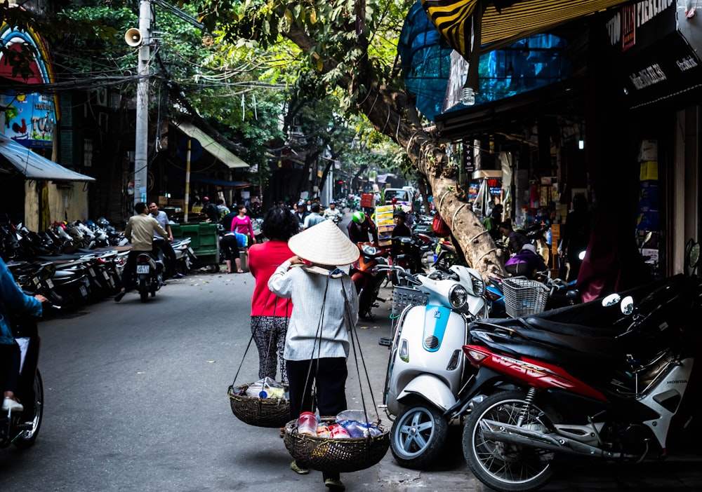 two women carrying baskets beside motorcycles during daytime