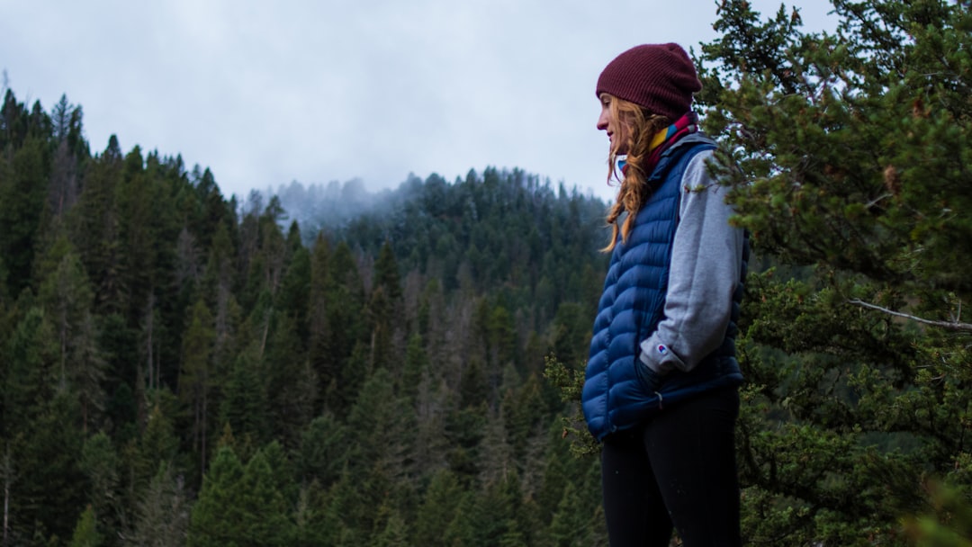 person in blue bubble jacket standing near tree lot during daytime