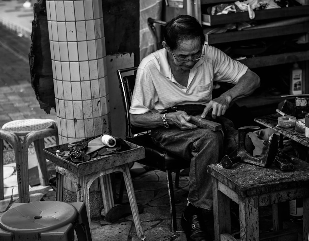 grayscale photo of man cleaning shoes