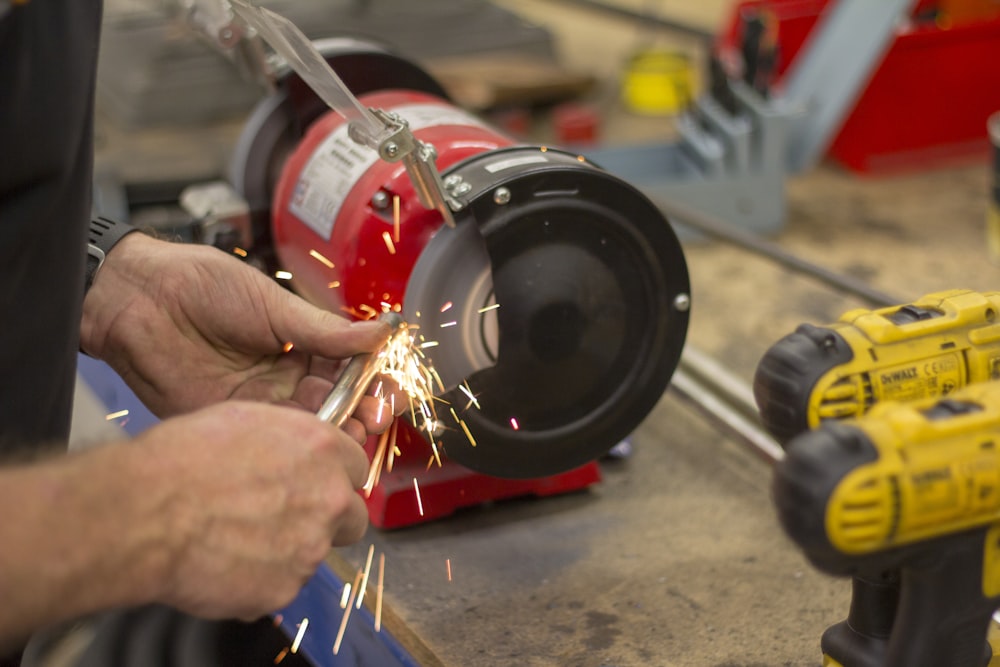 person in front of red bench grinder