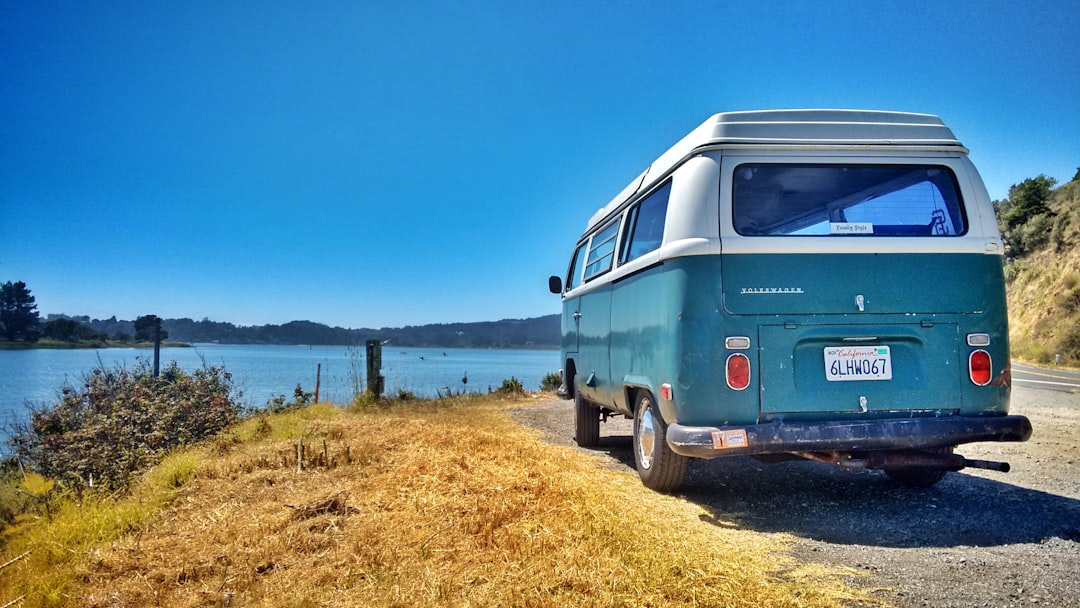 a van parked on the side of a road next to a body of water, Bus on the 1