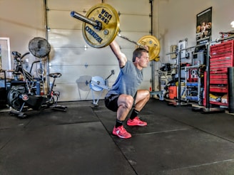 man in gray t-shirt lifting gray and yellow barbell