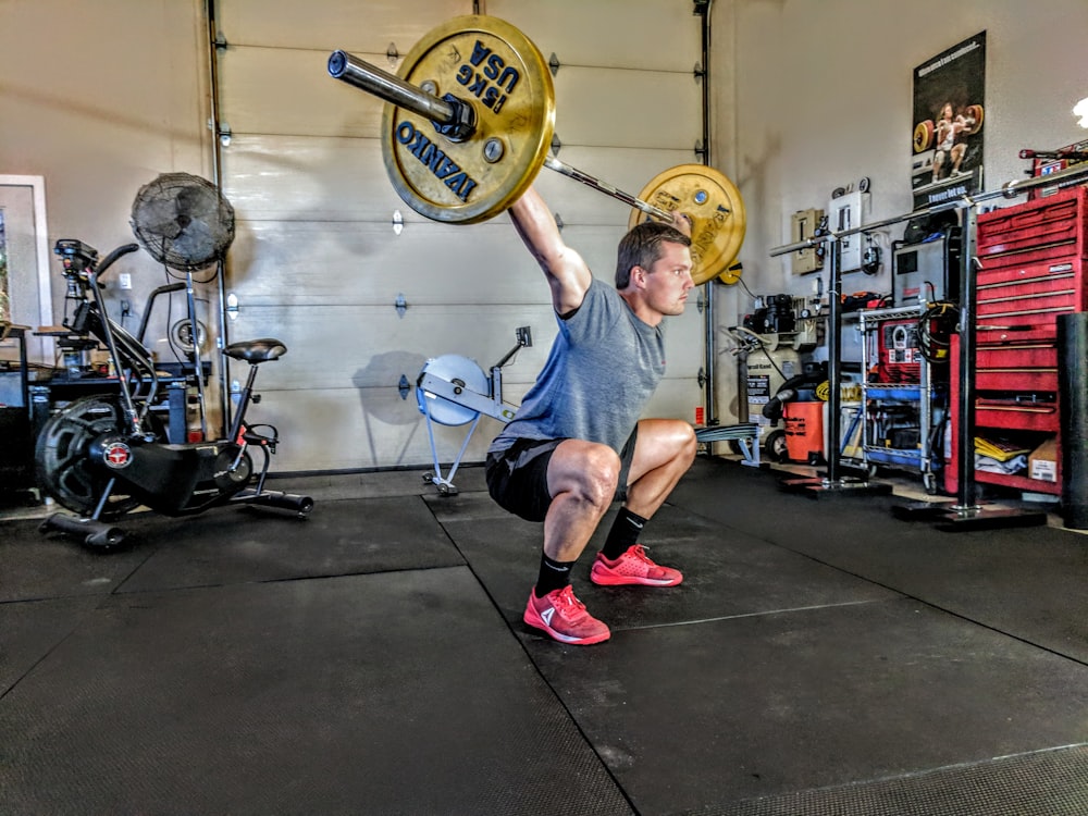 man in gray t-shirt lifting gray and yellow barbell