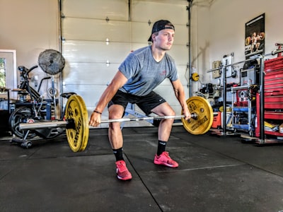 man carrying yellow barbell male teams background