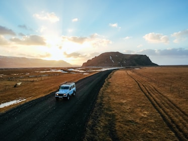 A scenic mountain road with a camper driving along at sunset.