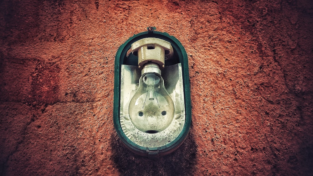 green framed clear bulb lamp on brown concrete wall