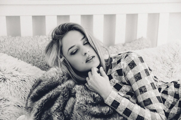 A cozy bedroom scene with a model lounging in a comfortable, stylish lingerie set, surrounded by soft pillows.