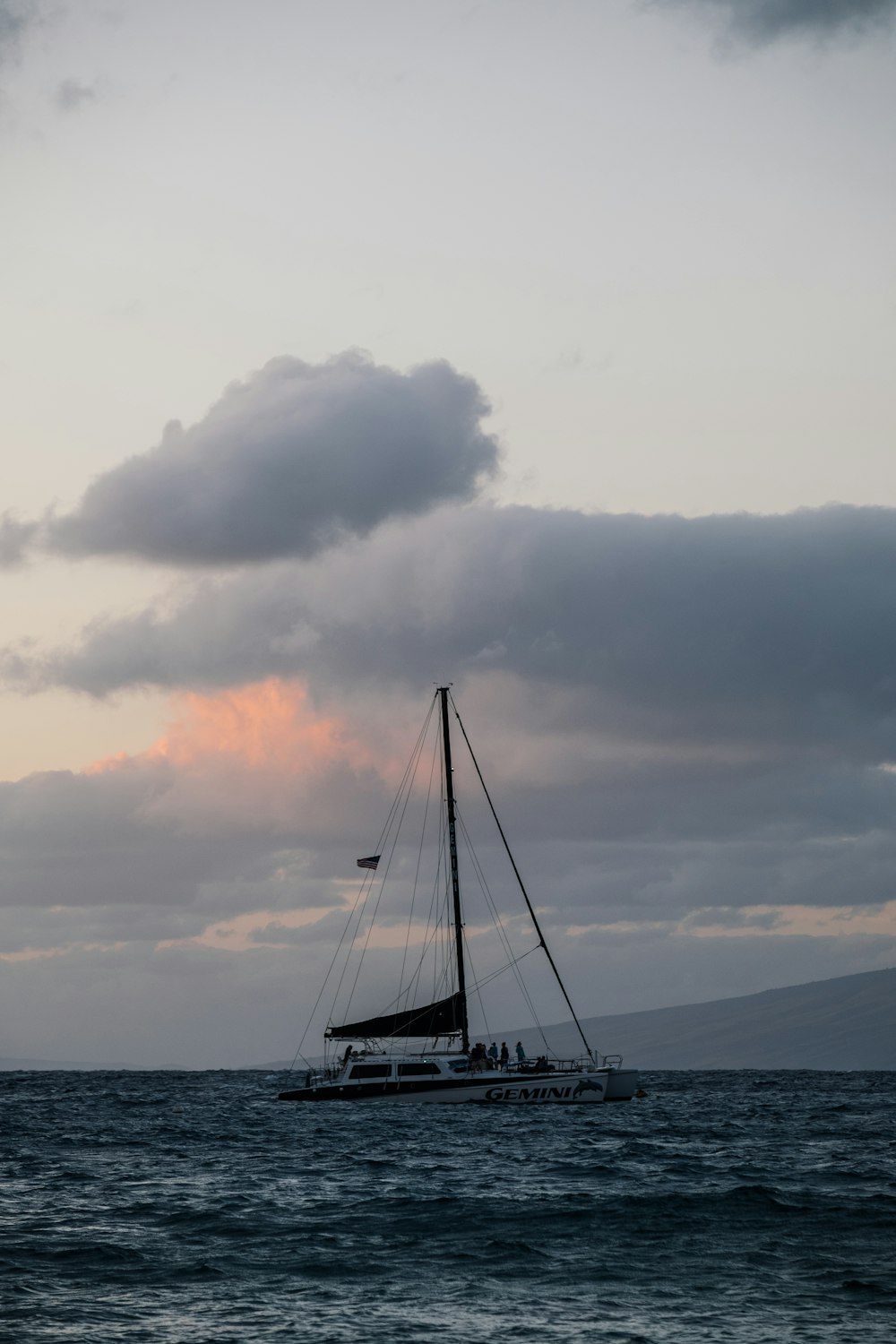 white sailboat bodies of water under cloudy sky at daytime