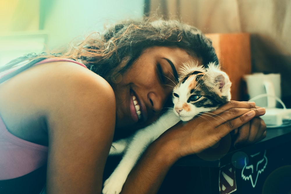 woman lying beside cat while smiling