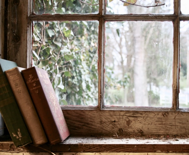 three books leaning on glass window