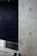 A minimalist interior space featuring a large concrete wall with visible construction markings and a metal railing in the foreground. The background is dark, adding contrast to the lighter tones of the concrete. The overall design is industrial and modern.
