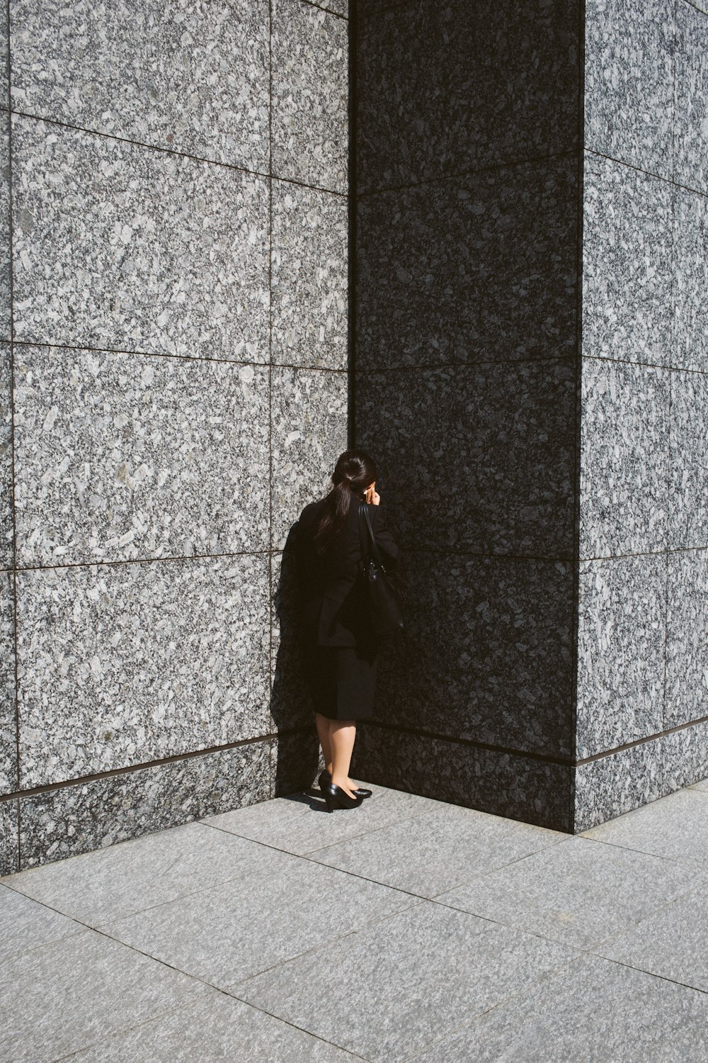 Frau in schwarzem Blazer und Rock mit Smartphone