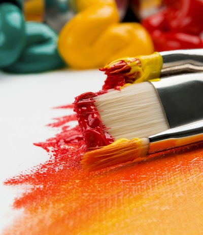 three silver paint brushes on white textile