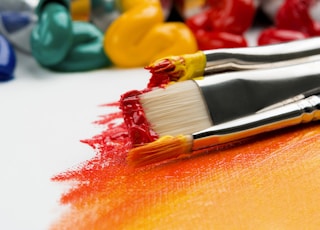 three silver paint brushes on white textile