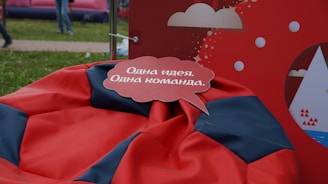 A speech bubble with text in the Russian language is placed over a red and black bean bag. The background features a red display with white cloud and circle graphics.