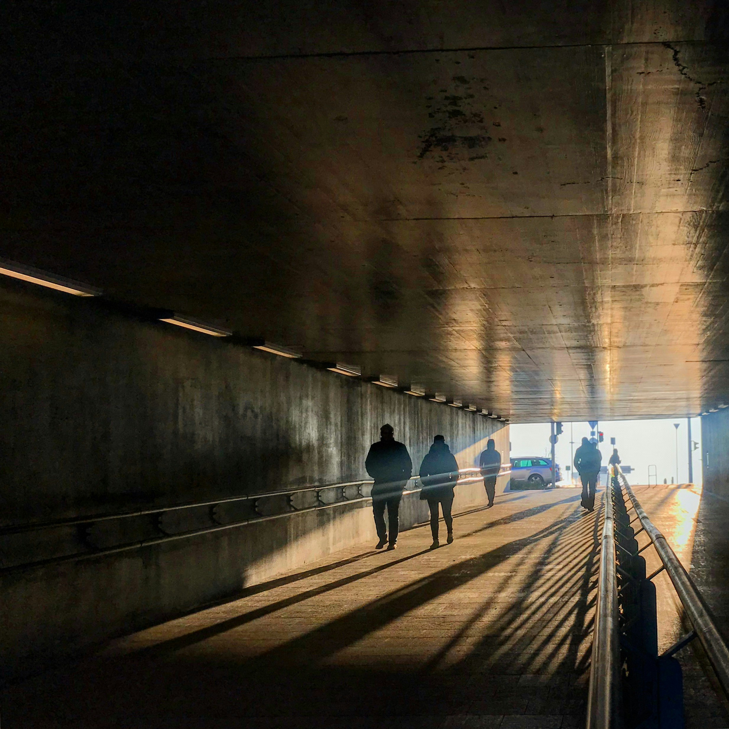 four people walking inside tunnel at daytime