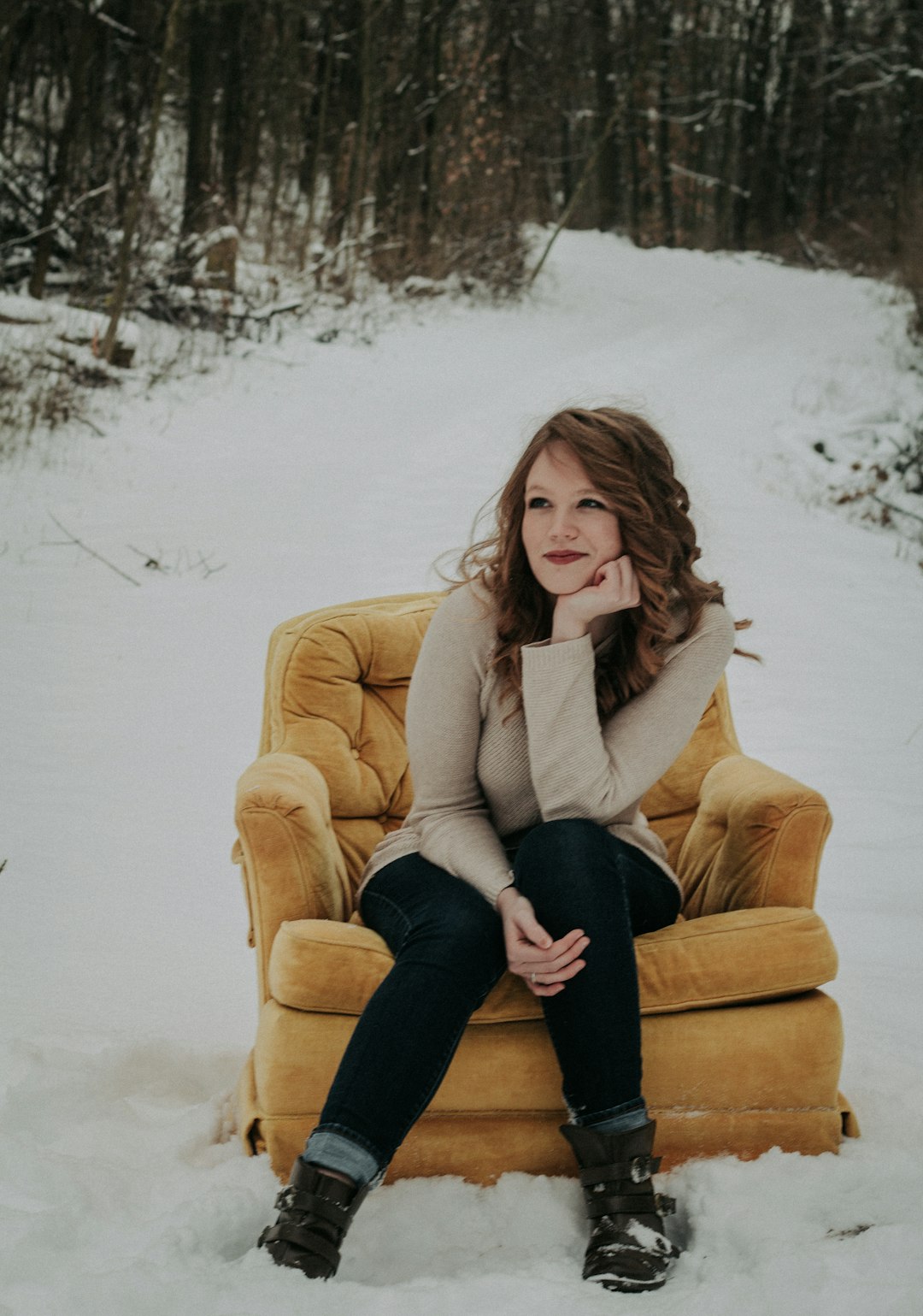 woman sitting on sofa chair surrounded with snow and trees