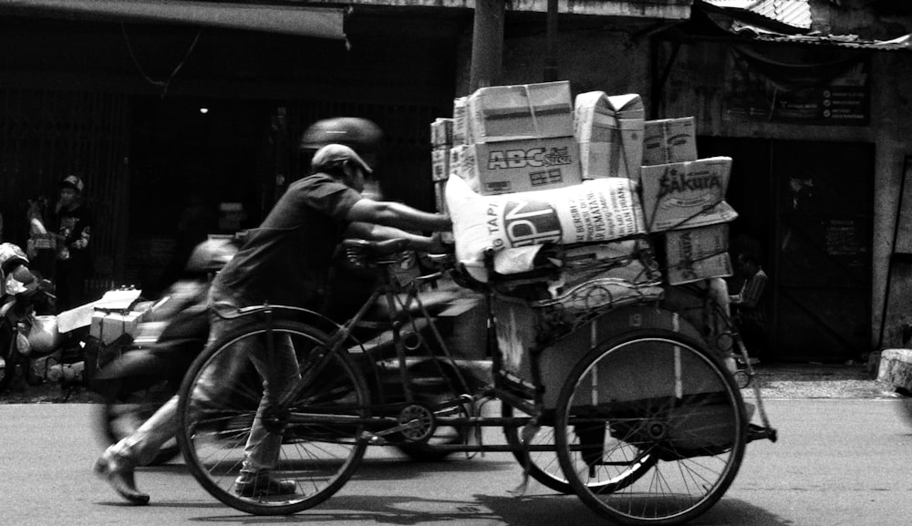 grayscale photo of man pushing cart on road during daytime