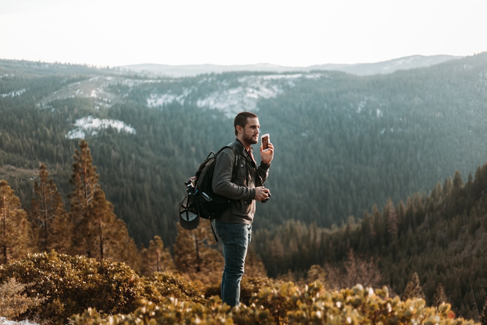 man wearing black jacket standing on mountain