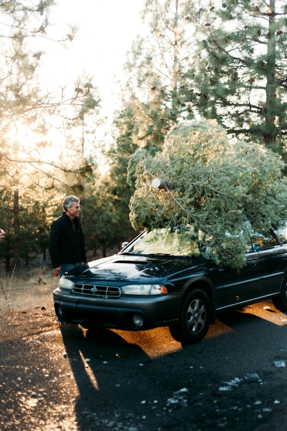 person wearing black jacket standing in front of blue vehicle during daytime