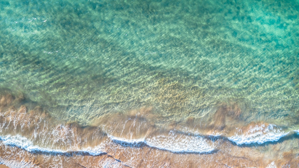 Photo aérienne d’une plage de sable brun avec des eaux vertes