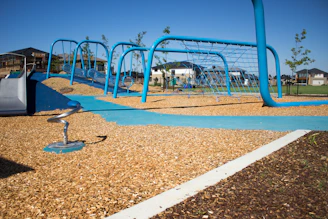 A vibrant playground with children playing on modern equipment under a clear blue sky.