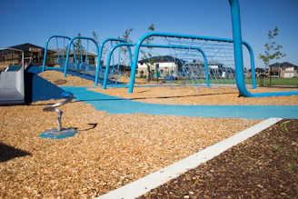 Children laughing and playing together on a safe, modern playground under a clear blue sky.
