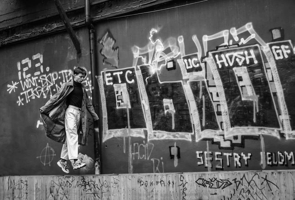 person walking on gray concrete wall beside graffiti