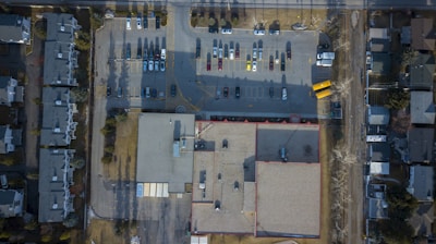 aerial photography of large building with vehicles on parking lot during daytime