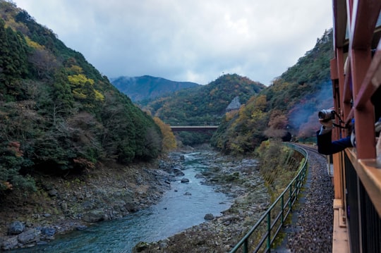 photo of a rocky river taken from inside train during day in Saga-Arashiyama Station Japan