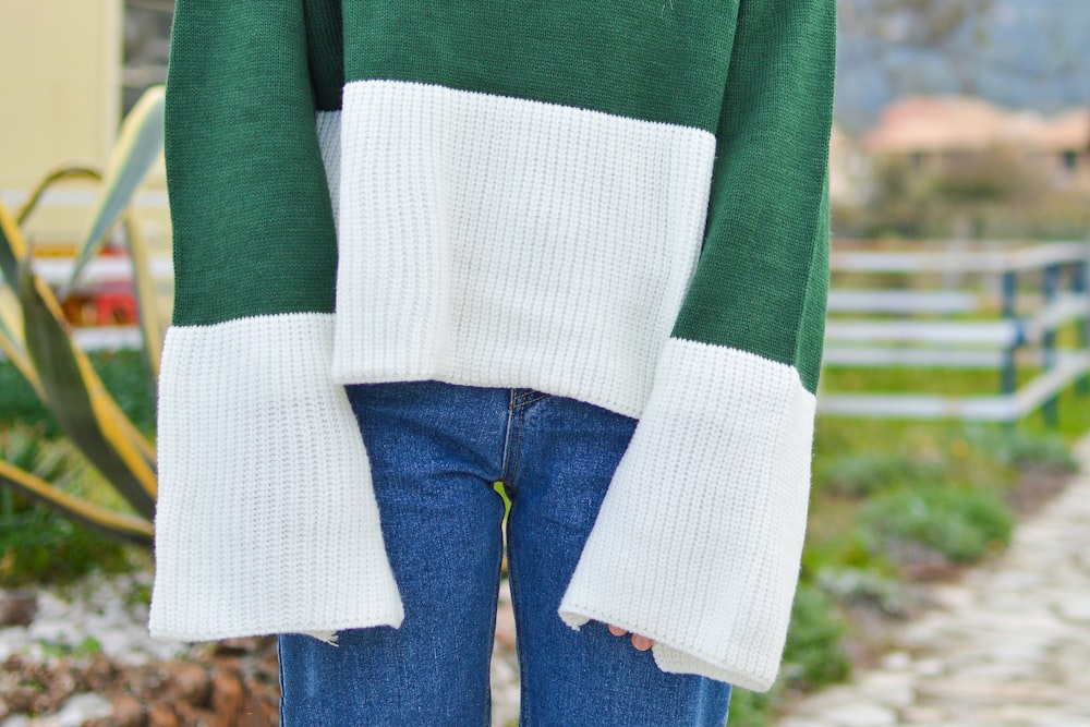 person wearing green and white long-sleeved top and blue denim bottoms