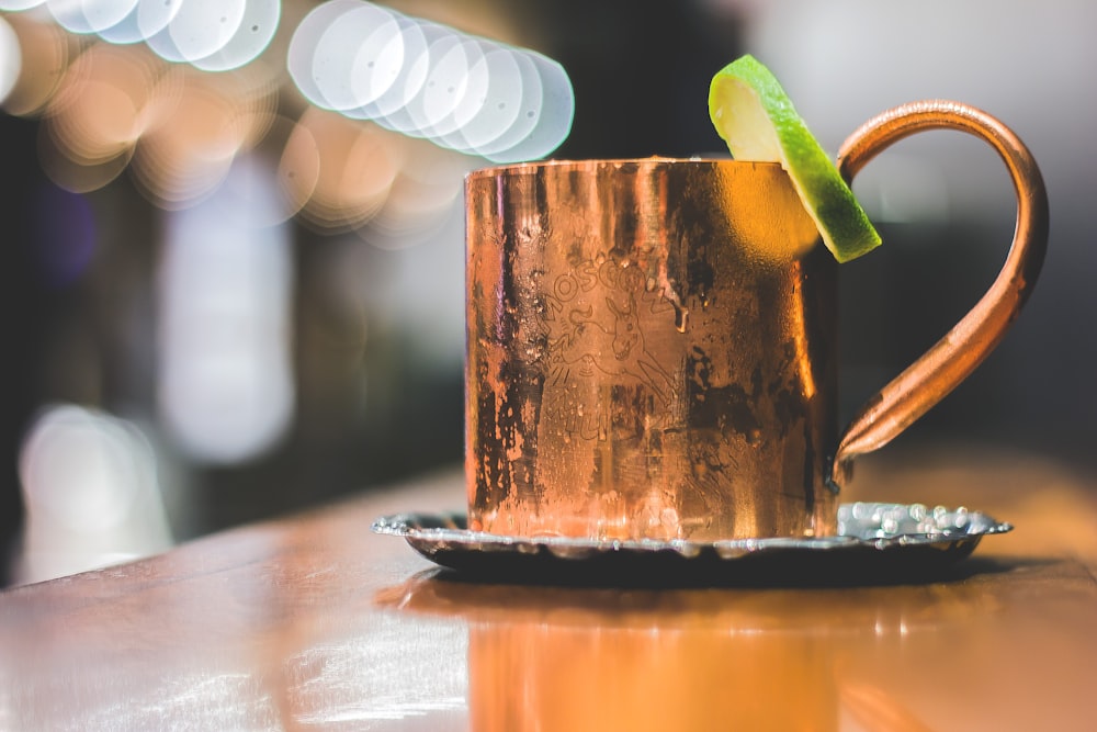 selective focus photo of brass-colored mug