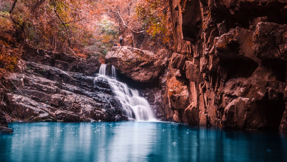 waterfalls surrounded by rocks during daytime