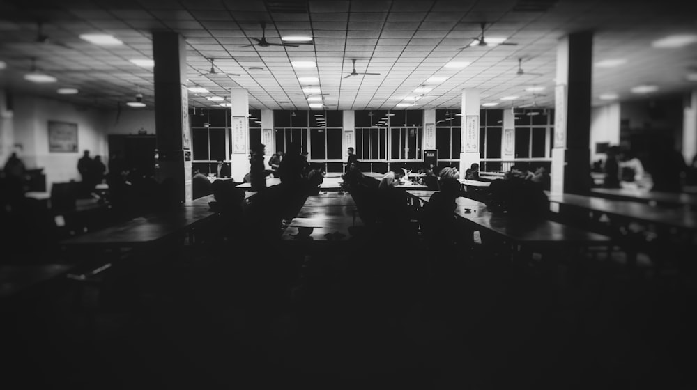 grayscale photo of room filled with tables