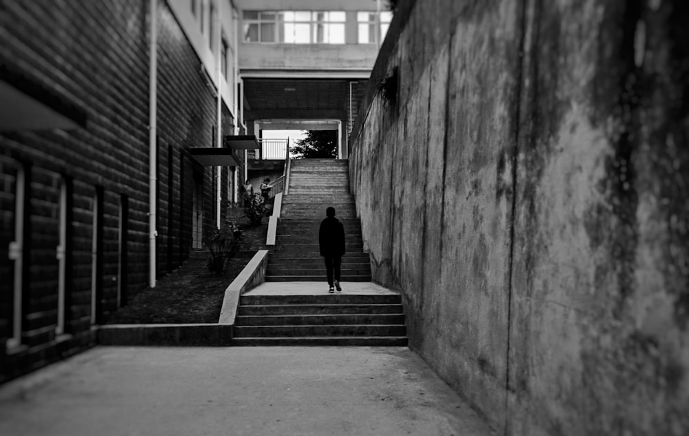 grayscale photography of person standing on stairs heading up