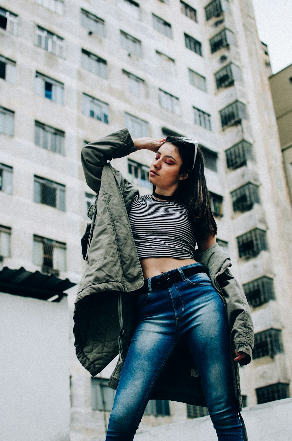 woman wearing crop top and denim pants standing near high rise building