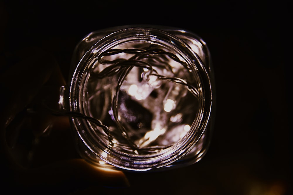 a hand holding a jar with a string of lights inside of it