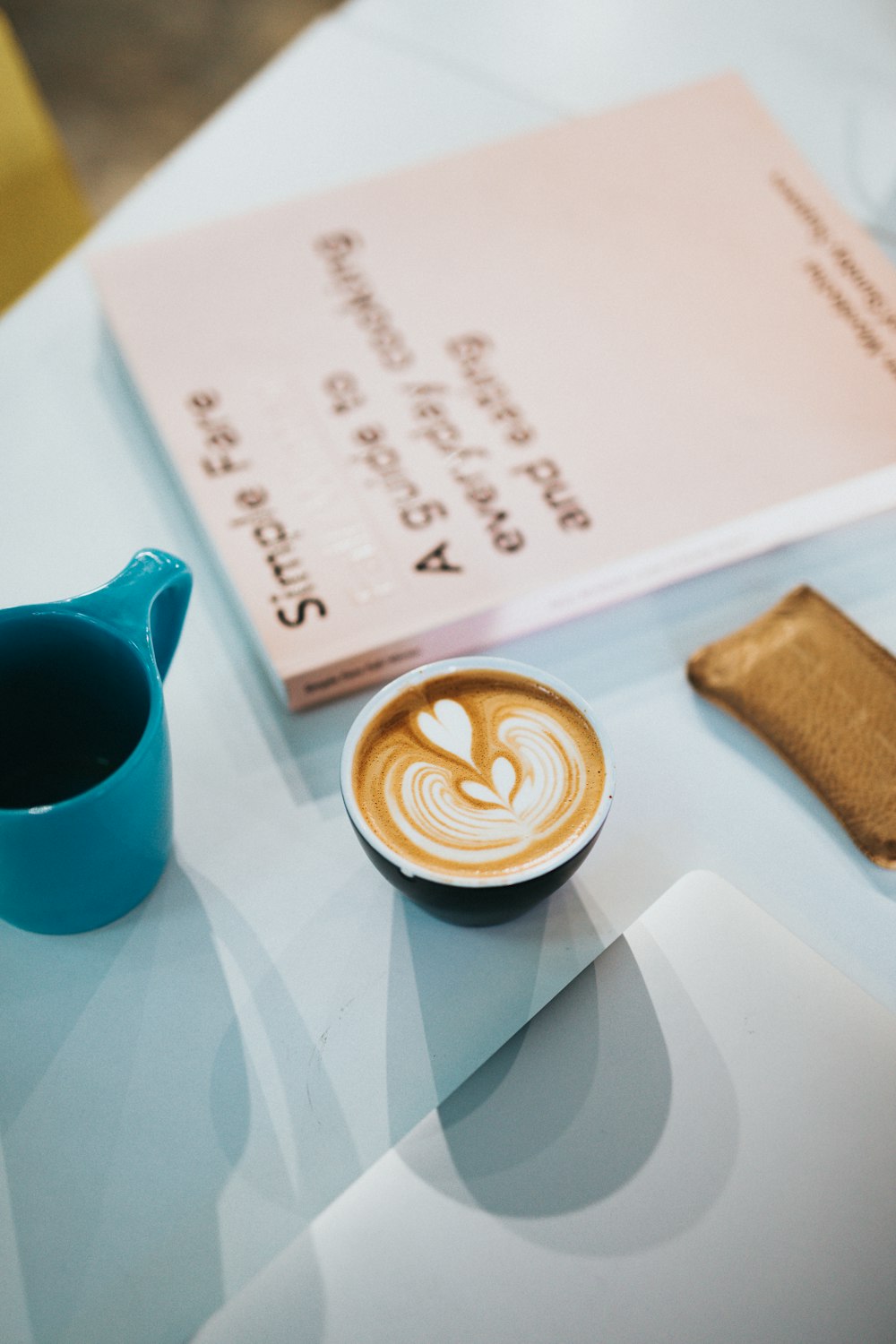 coffee filled ceramic mug beside book