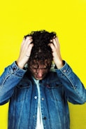 man in blue denim jacket holding his hair