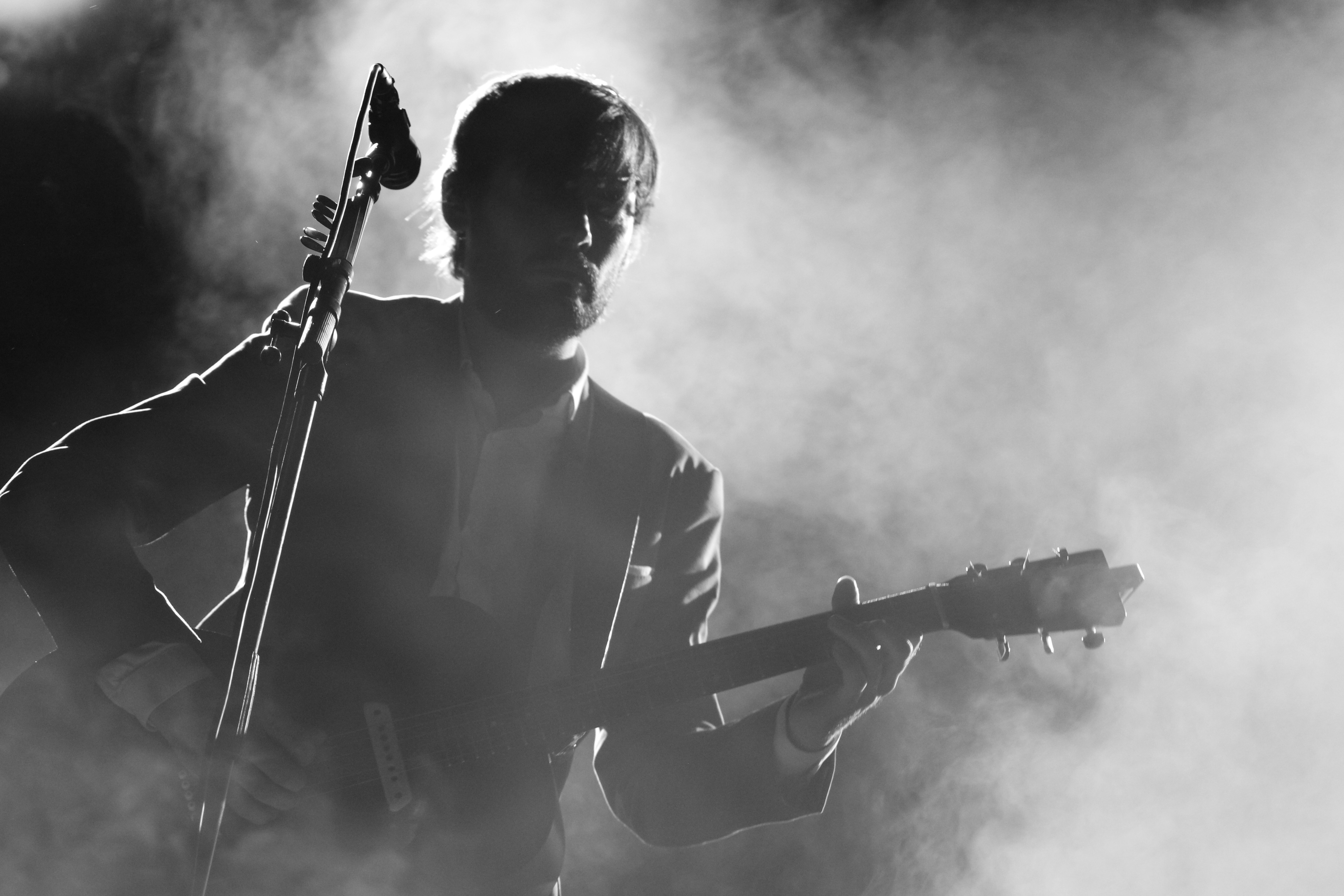 マイクの横にギターを弾く男のシルエット